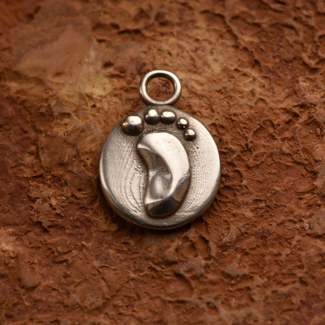 Сребърен медальон 925 „Амулет за нов живот“ – ръчно изработен талисман с бебешко краче, символ на чистота и семейна любов, бохо-рустик скулптурно бижу от Арт Дива, заснето върху топъл каменен фон.