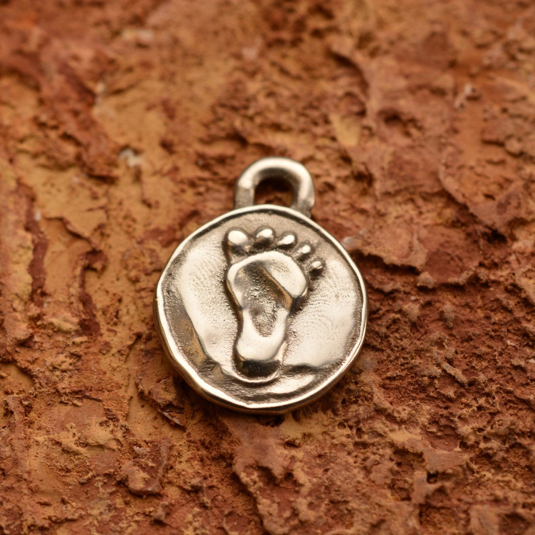 Сребърен медальон 925 „Бебешко краче“ – ръчно изработен талисман на новото начало, любовта и семейната обич, бохо-рустик скулптурно бижу от Арт Дива, заснето върху топъл каменен фон.