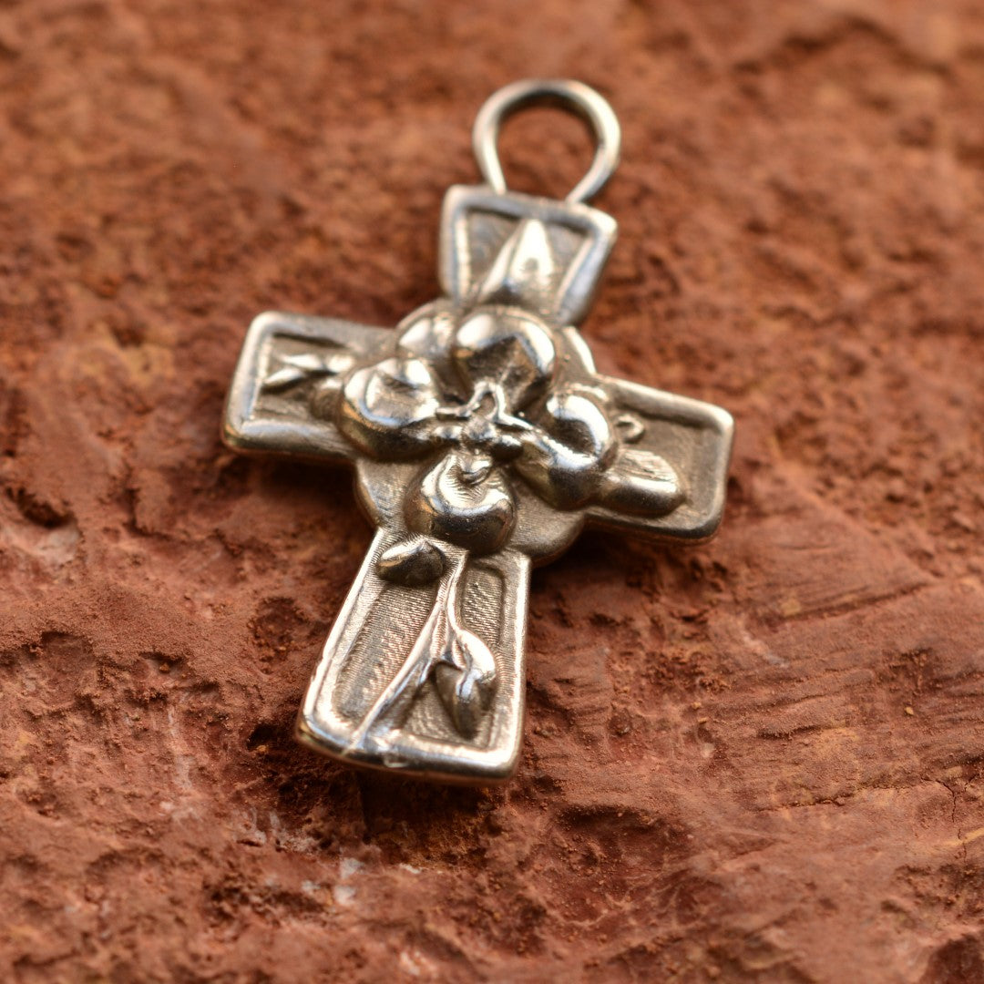 Сребърен медальон 925 „Кръст с цветя“ – ръчно изработен талисман на вярата, любовта и новото начало, бохо-рустик скулптурно бижу от Арт Дива, заснето върху топъл глинен фон.