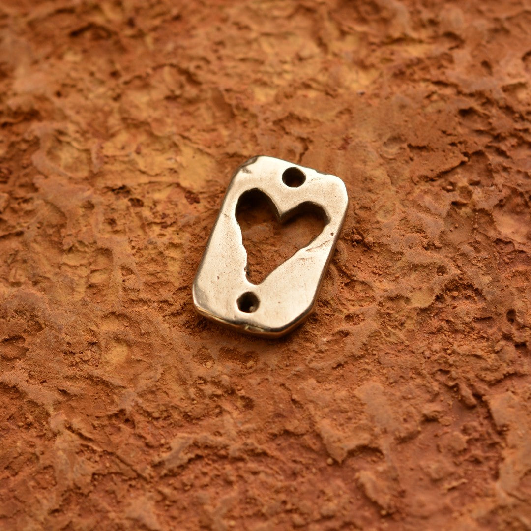 Сребърен медальон 925 „Сърце“ – ръчно изработен амулет на любовта и защитата, бохо-рустик скулптурно бижу от Арт Дива, заснето върху кафяв камък с текстура.