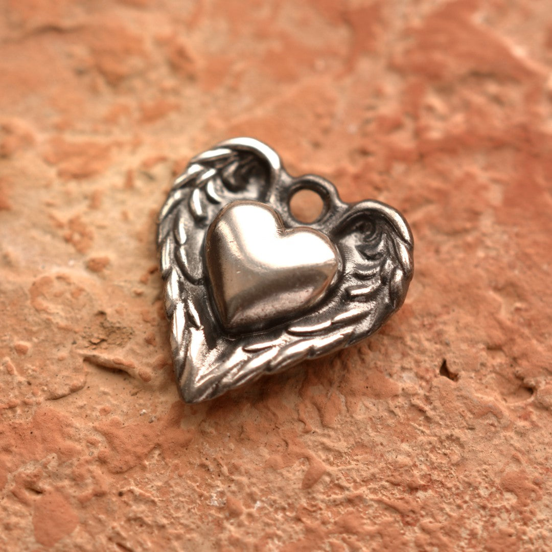 Сребърен медальон 925 „Сърце с ангелски крила“ – символ на закрила, любов и духовна сила, ръчно изработено бохо-рустик скулптурно бижу от Арт Дива, заснето върху топъл каменен фон.