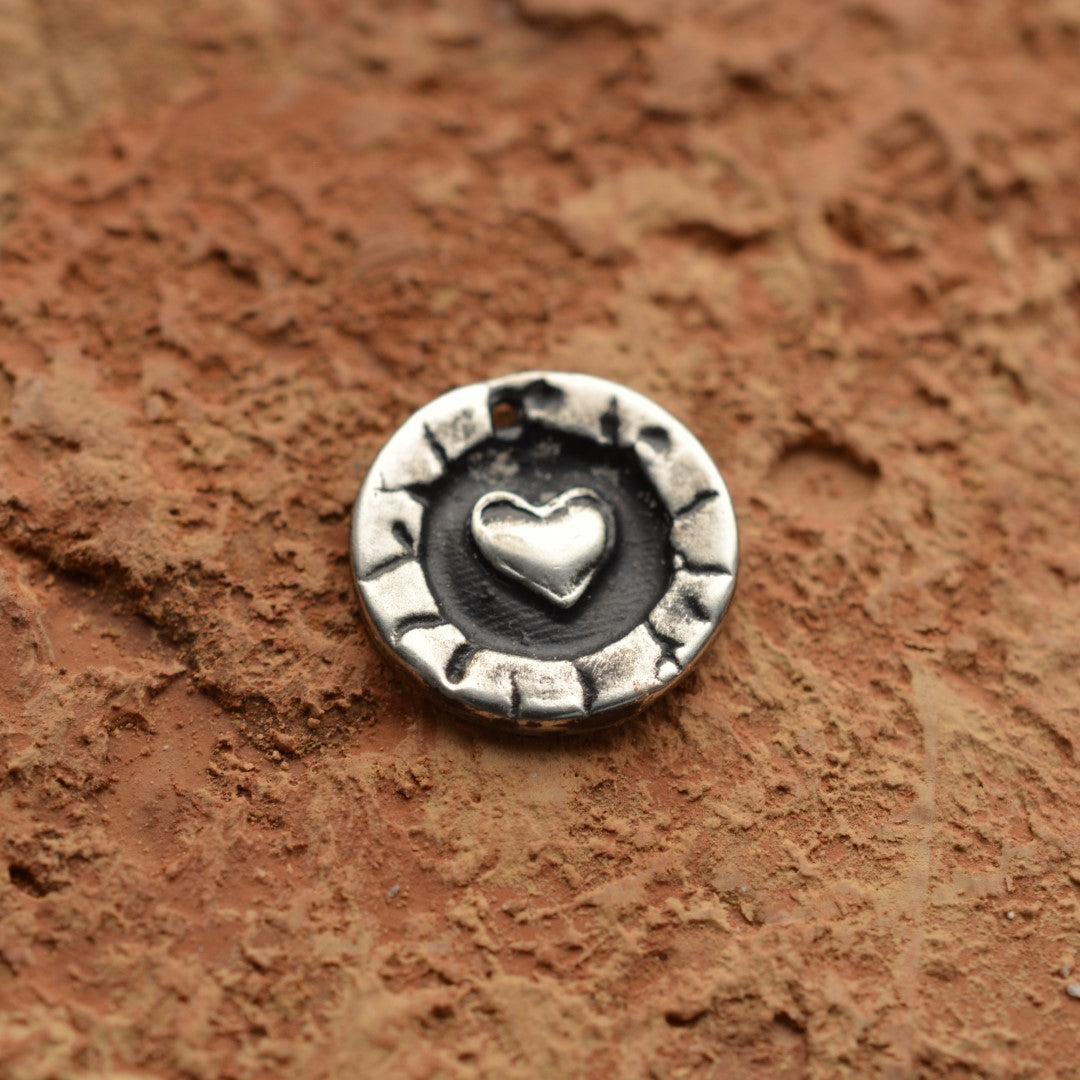 Сребърен медальон 925 с релефно сърце – ръчно изработен талисман на любовта и закрилата, бохо-рустик скулптурно бижу от Арт Дива, заснето върху каменен фон.