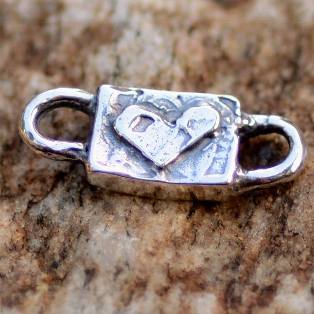 Сребърен свързващ елемент 925 „Сърце“ – талисман за любов и нежност, ръчно изработено бохо-рустик скулптурно бижу от Арт Дива, заснето върху каменен фон.