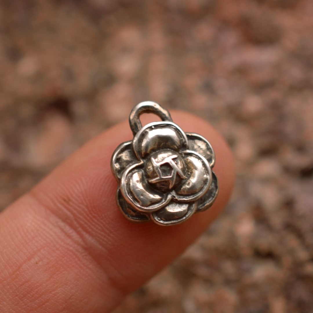 Сребърна висулка 925 „Камелия“ – ръчно изработен амулет на красота и елегантност, бохо-рустик скулптурно бижу от ArtDiva, заснето върху пръст и гранитен фон.