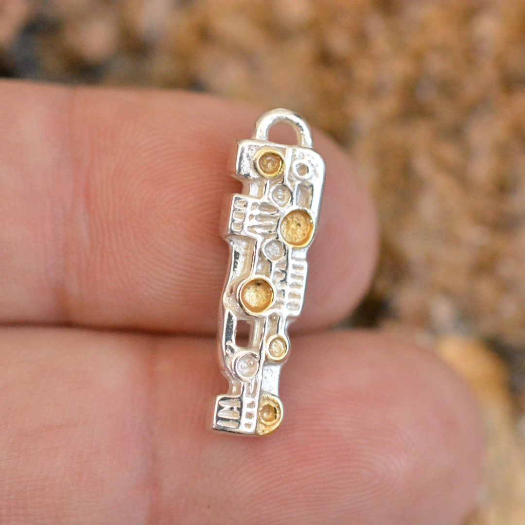 Сребърна висулка 925 „Пулс“ със златни акценти – ръчно изработено артистично скулптурно бижу, символ на сила и ритъм, бохо-рустик стил от ArtDiva, заснето върху пръст.