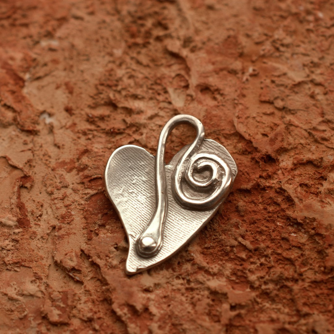 Сребърна висулка 925 „Сърце и спирала“ – ръчно изработен талисман за любов и ново начало, бохо-рустик скулптурно бижу от Арт Дива, заснето върху каменен фон.