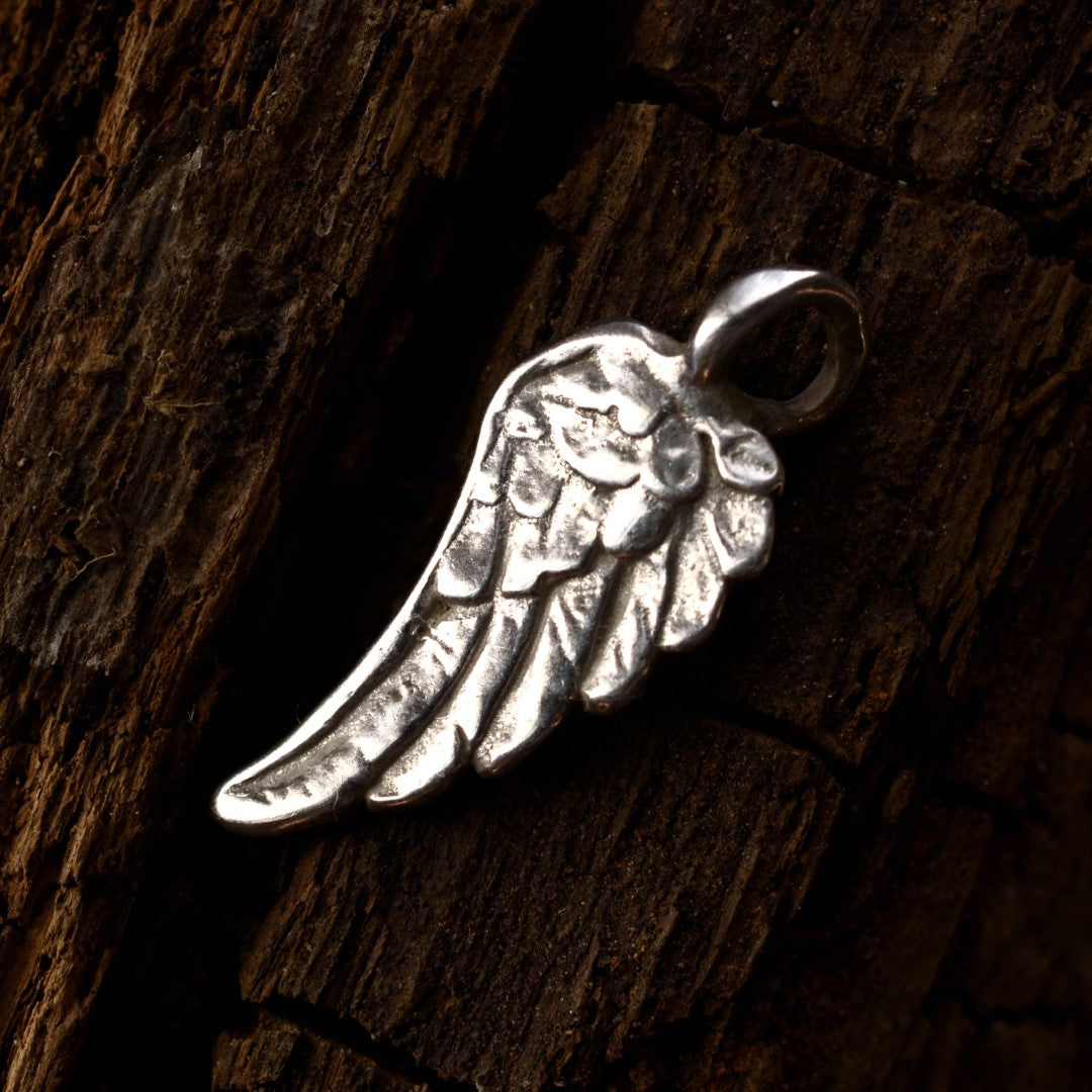 Сребърна висулка 925 „Ангелско крило“ – ръчно изработен амулет за закрила и надежда, бохо-рустик скулптурно бижу от ArtDiva, заснето върху тъмен дървесен фон.