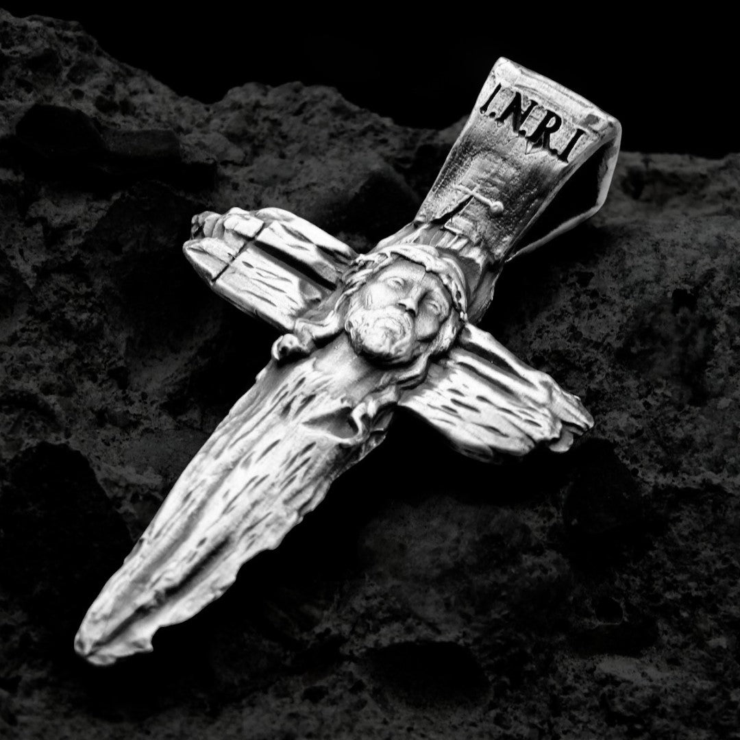 Сребърен кръст 925 с образ на Исус Христос – символ на вярата, надеждата и духовната закрила, ръчно изработен религиозен медальон в бохо-рустик стил от Арт Дива, заснет върху тъмен каменен фон.
