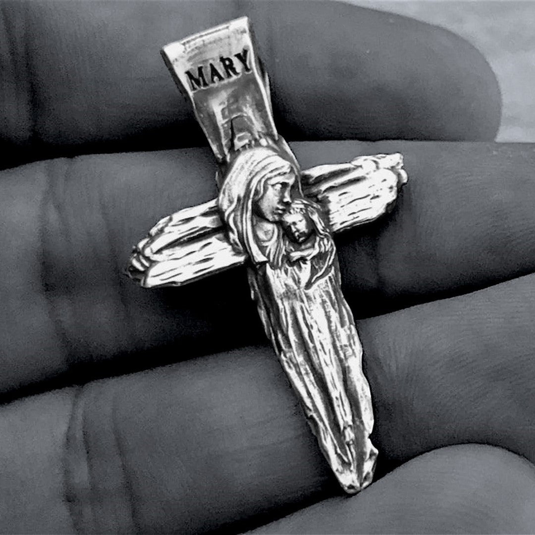 Сребърен кръст 925 с релефен образ на Дева Мария и Младенеца – символ на вяра, закрила и майчината любов, ръчно изработен скулптурен медальон от Арт Дива в бохо-рустик стил, заснет на тъмен фон.
