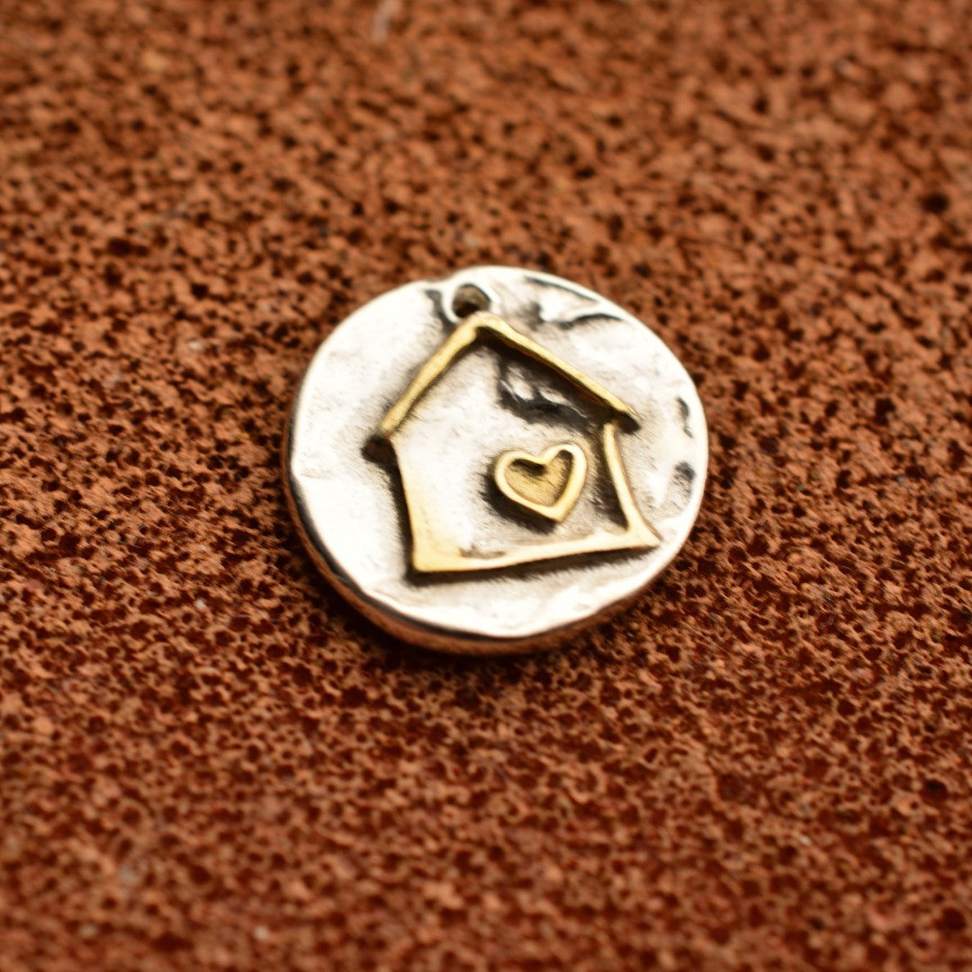 Сребърен медальон 925 „Домът е всичко“ със златни акценти – ръчно изработен талисман на любовта, уюта и семейната топлина, бохо-рустик скулптурно бижу от Арт Дива, заснето върху топъл кафяв фон.

