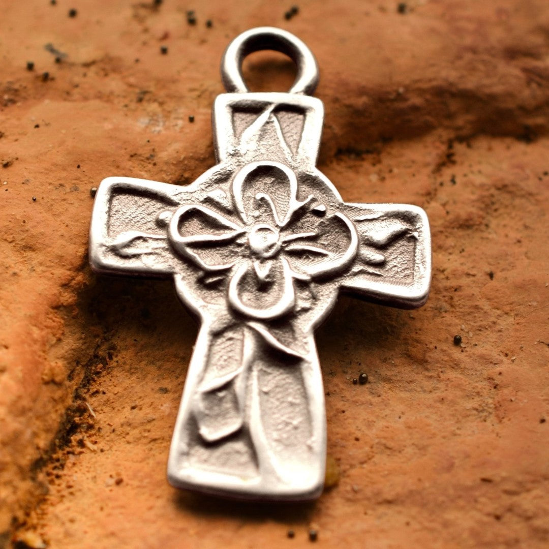 Сребърен медальон 925 „Кръст с цвете“ – ръчно изработен талисман и амулет на вярата и надеждата, със скулптурна текстура и рустикален характер, изработен от Арт Дива, заснет върху каменен фон.
