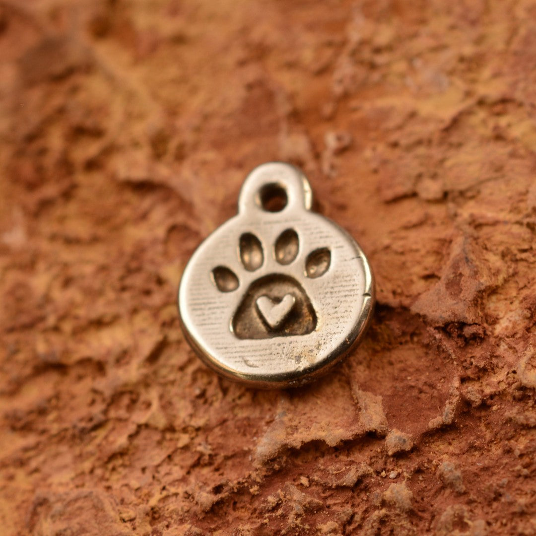 Ръчно изработен сребърен медальон 925 „Лапа със сърце“ – амулет на любовта към животните и верността, бохо-рустик скулптурно бижу от Арт Дива, заснето върху топъл каменен фон.
