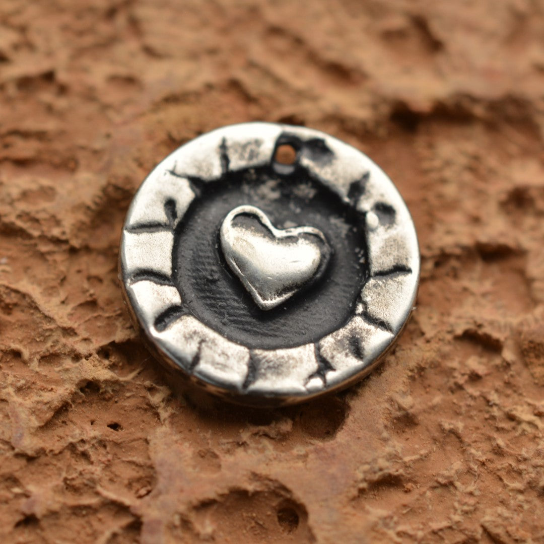 Сребърен медальон 925 с релефно сърце – ръчно изработен талисман на любовта и закрилата, бохо-рустик скулптурно бижу от Арт Дива, заснето върху каменен фон.
