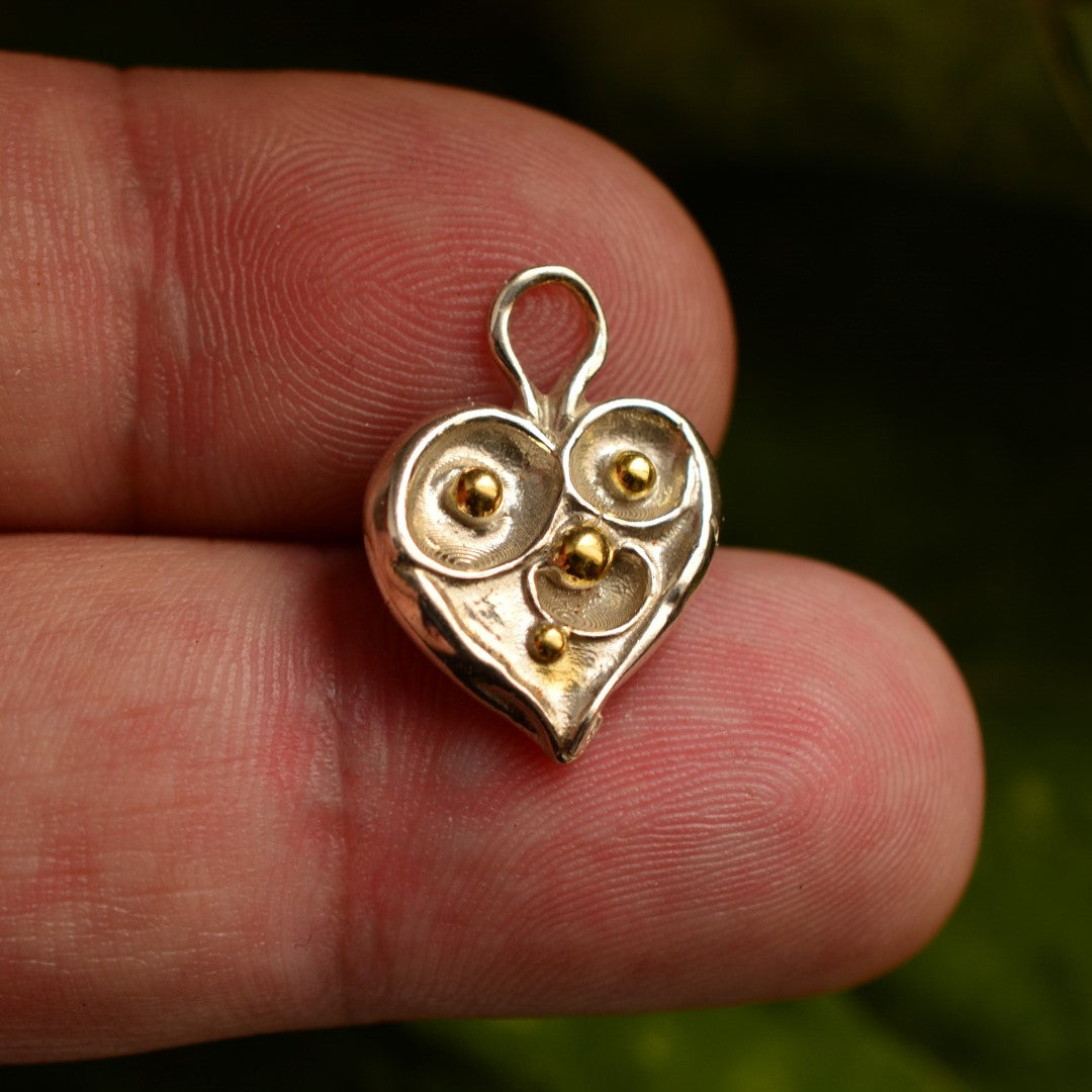 Сребърен медальон 925 „Сърце с капчици роса“ със златни акценти – ръчно изработен талисман на чистата любов и новото начало, бохо-рустик скулптурно бижу от Арт Дива, заснето върху естествен зелен фон.
