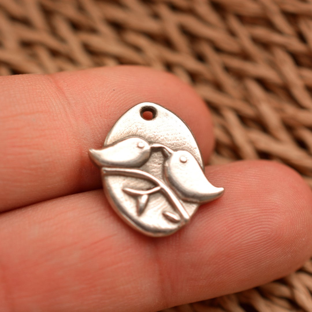 Сребърен медальон 925 „Влюбени пиленца“ – ръчно изработен талисман на любовта, нежността и хармонията, бохо-рустик скулптурно бижу от Арт Дива, заснето върху естествен фон от плетена текстура.
